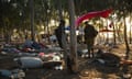 A solider stands among debris from tents amid trees