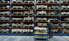 A man pushes a trolley by high shelves of stone objects